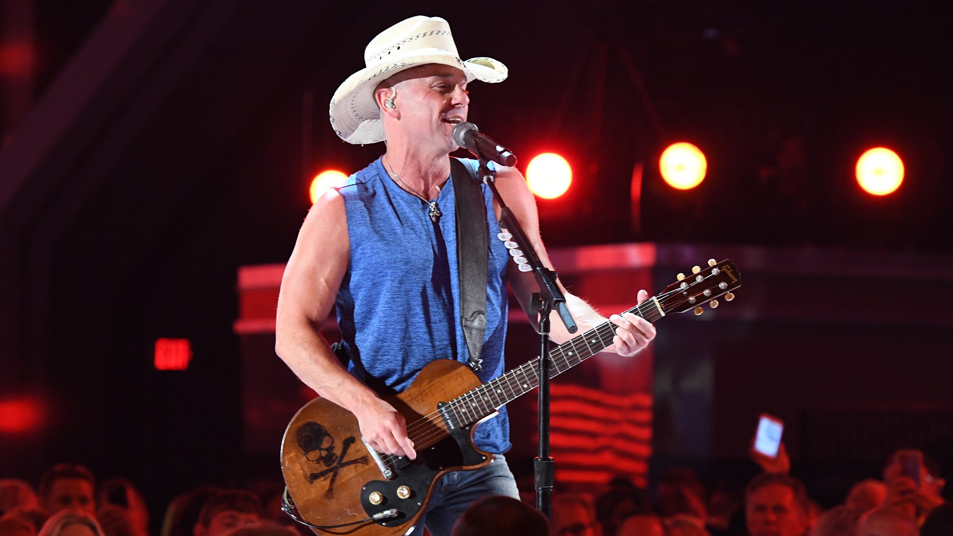 A sleeveless Kenny Chesney hits the stage first and performs his latest single,